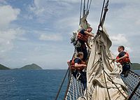 Coast Guard Academy cadets learn how to furl sail on the Eagle's bowsprit under the tutelage of a petty officer while sailing among the British Virgin Islands in 2013.