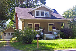 A brown house with small front lawn and garage to the rear on the left