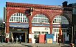 A red-bricked building with a dark blue, rectangular sign reading "LAMBETH NORTH STATION" in white letters all under a light blue sky