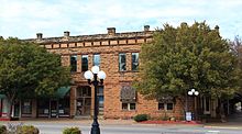 A two-story stone building on a downtown street.