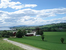 Foto einer am Meer gelegenen Landschaft, in der verstreut mehrere Häuser liegen