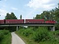 Eine Diesellokomotive der Baureihe V 60 mit Waggons auf der Ilmenaubrücke des Nordteils im Industriegebiet Lüner Heide.