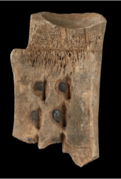 Back of a bone fragment, with scorch marks and an inscription on the right