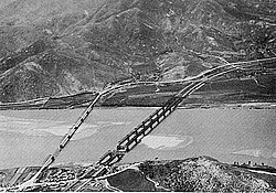 A River with two bridges extending over it, and a large hill on the south bank