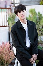 Jin, in a black suit facing towards the camera