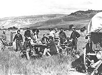 A noon meal in Ferdinand V. Hayden's camp of the U.S. Geological and Geophysical Survey. Red Buttes, Wyoming Territory, August 24, 1870. Hayden sits at far end of table in dark jacket. (Photo by William Henry Jackson standing at far right, 1870)