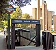 A green sign with the words "WARWICK AVENUE STATION" written in white letters on a dark blue rectangle all under a light blue sky with white clouds