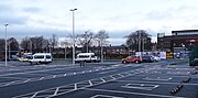 A concrete carpark with houses and a shopping centre in the background