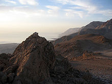 Elevated, barren, and rugged terrain next to a large body of water