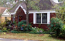 A small, one-story brick-faced house with a small yard in front