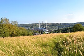 Photograph of a landscape. In the foreground, fields; in the background, a power plant.