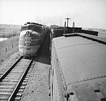 A DL-109 pulls a Santa Fe passenger train past a freight train