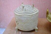 A footed Western Han white ceramic wine warmer with animal-head figurines decorating its lid