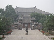Several buildings are on an axis in front of one another, with the main hall at the end, partially obscured by the buildings in front.