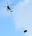 A helicopter moving cedar wood from the inside of a forest to a road.