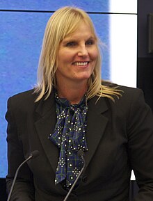 Swimmer Sylvia Poll show from the waist up wearing a suit in front of a podium