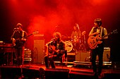 A picture of three men playing guitars on a stage