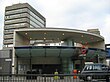 A grey building with a rectangular, dark blue sign reading "SOUTHWARK STATION" in white letters all under a light blue sky with white clouds