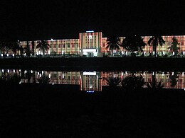 Lighted building at night, reflected in water