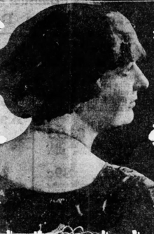 A white woman with dark hair, photographed in profile, back to camera