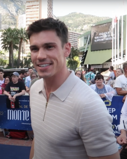 A man with brunette hair, wearing a greens suit.