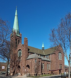 Massive brownstone church with a tall corner steeple