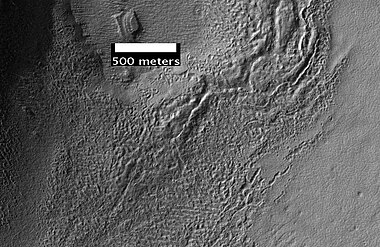 Surface of Debris Apron. There is also a feature similar to features in Red Rocks Park, Colorado. Feature seems to be composed of slanted rock layers. Image taken with HiRISE, under the HiWish program.