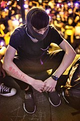 Protester with "#ProtestToo" written on their arm with lipstick