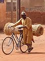 A man uses a bicycle to carry goods in Ouagadougou, Burkina Faso