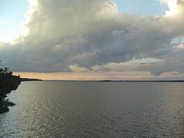 A body of water under a cloudy day sky.