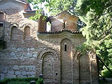 Ausschnitt der rechten Seite einer Mauer einer Kirche, die sichtbaren Steine und vermauerten Fenster sind terracottafarben