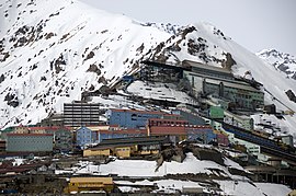 Links unten die Häuser der verbliebenen Wohnstadt mit ihren charakteristischen bunten Farben. Rechts oben das Hüttenwerk mit der Schienenrampe am Ende des Tunnels zur Grube, Gesteinsmühle und Konzentratoranlage. (Bild 2008)