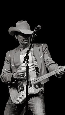 A black-and-white image of George Ducas playing an electric guitar