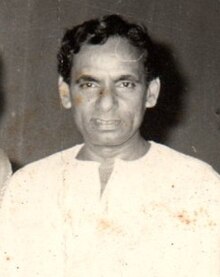 a black and white photograph of a South Asian man in a white shirt with short black hair