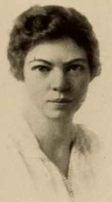 A young white woman with short dark hair, wearing a white blouse