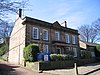 A stone building with five bays and a central porch supported by columns