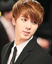 Jin, wearing a formal black suit at an award ceremony