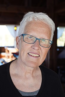 Photo of a woman's face with cropped grey hair and wearing glasses