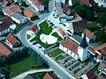 Luftaufnahme von Gansheim: dominant im Bild der östliche Teil der Regilostraße; in der Bildmitte der 2010 neu erbaute Dorfplatz, rechts daneben die Kirche St. Nikolaus