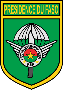 A badge with a parachute and two wings, the roundel of Burkina Faso and a dagger. Around the roundel is written in French État-Major Particulier (Personal Staff). A rectangle at the top of the badge contains the words Présidence du Faso (Presidency of the [Burkina] Faso)