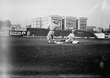 A black-and-white photograph of a baseball player sliding into a base