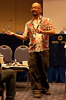 A balding Japanese man in a Hawaiian shirt.