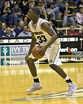 an African American basketball player in a Purdue #33 jersey is dribbling a basketball