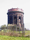 A circular stone tower with pilasters and arches, carrying an iron tank