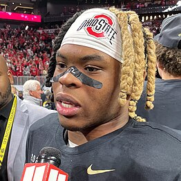 A football player talking to microphone on a football field.