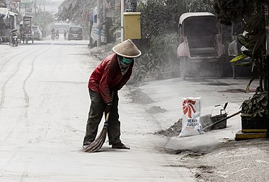 Man sweeping volcanic ash