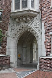 Photo depicts an open pedestrian passageway through one wing of Sledd Hall, a red brick and carved stone student dormitory at the University of Florida, built in 1929 in the then-popular collegiate gothic architectural style