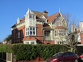 Three story red brick house with white and sea green colored trim.