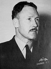 Portrait of moustachioed man in dark military uniform with pilot's wings on left pocket