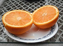 An orange on a white plate that has been divided in half.